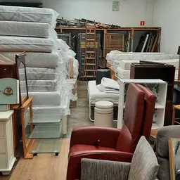 Uitgestalde tweedehandsmeubels in de winkel: matrassen, stoelen, kasten en andere meubelstukken