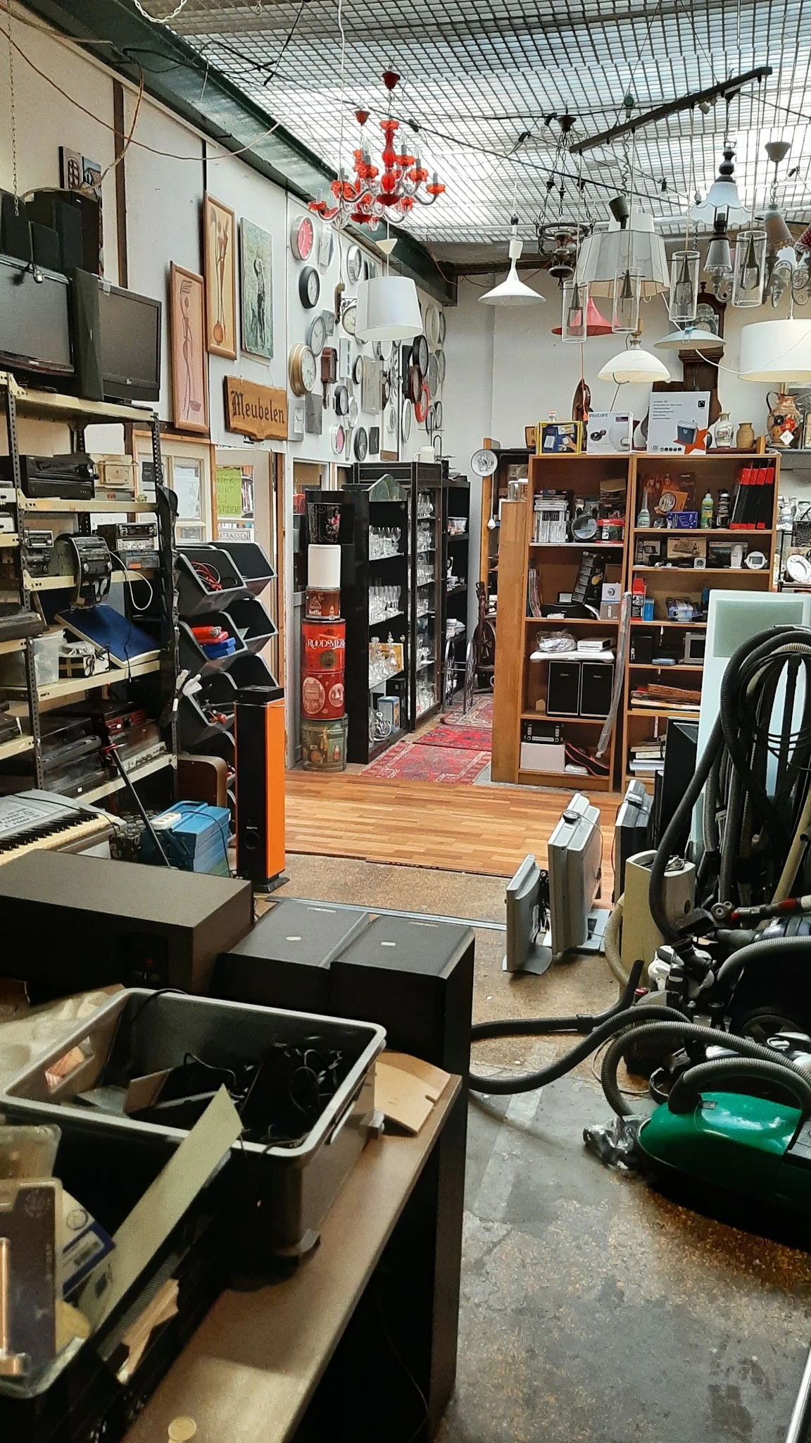 Winkelinterieur met houten vloer, stellingen met gebruikswaar, zwarte opbergkast en diverse artikelen langs de wanden