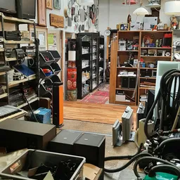 Winkelinterieur met houten vloer, stellingen met gebruikswaar, zwarte opbergkast en diverse artikelen langs de wanden