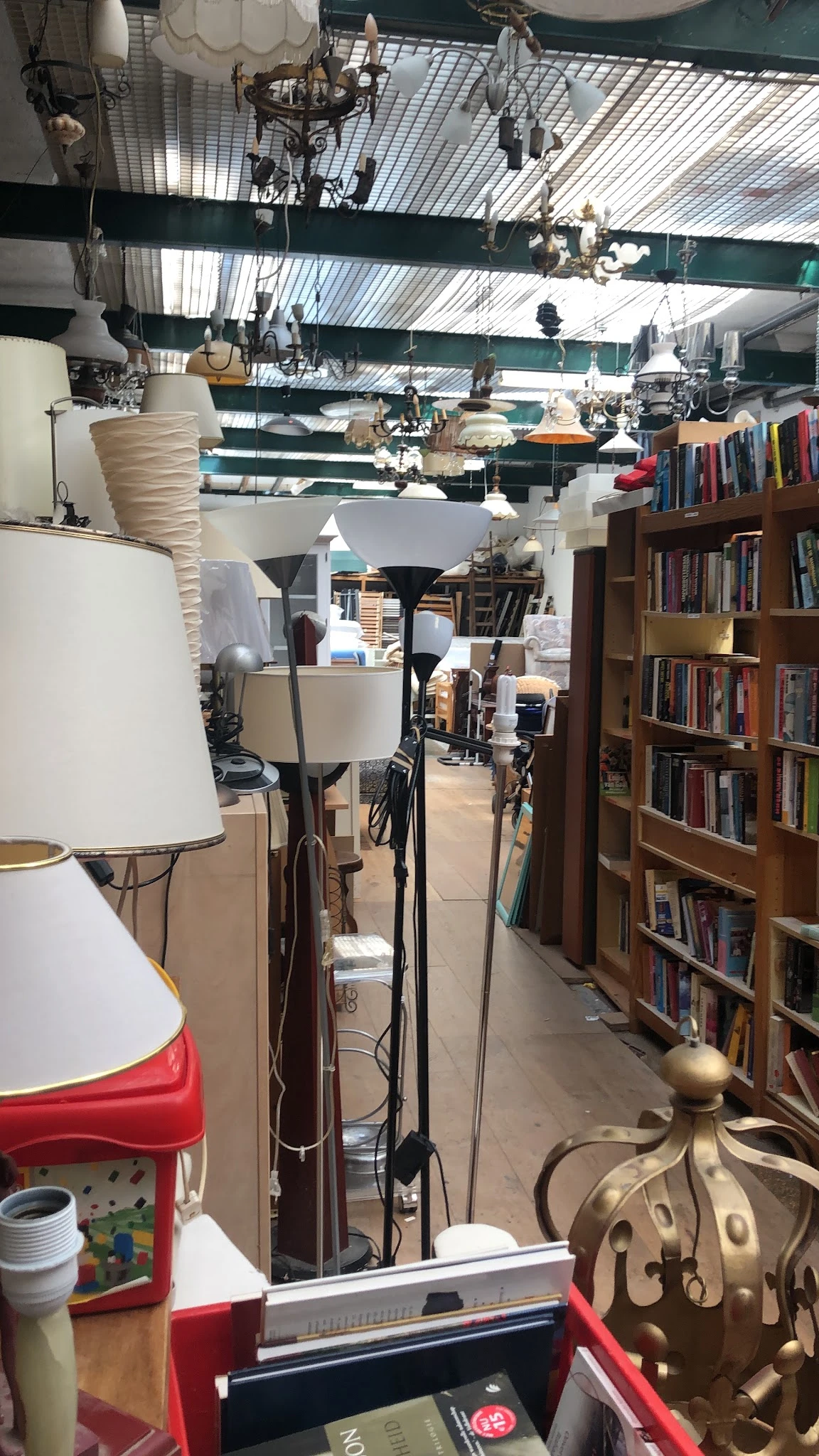 Winkelinterieur met boekenkast, lampen, fietsen en diverse spullen in een kringloopwinkel