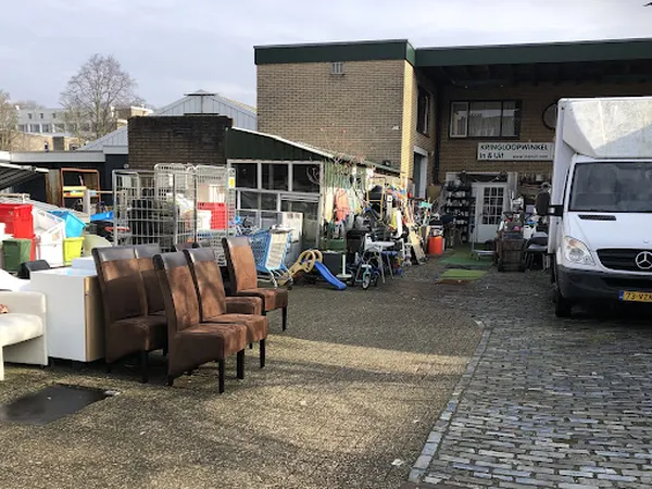 Exterieur van kringloopwinkel met bruine stoelen en spullen buiten op het terrein