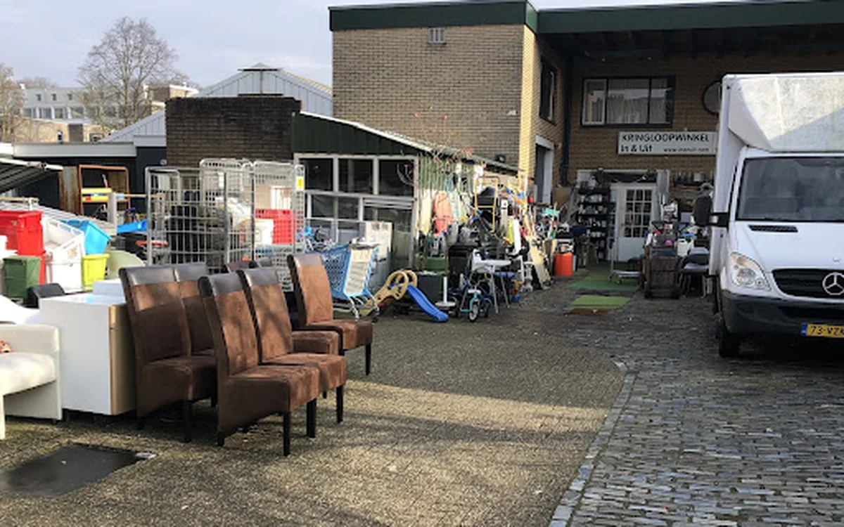 Exterieur van kringloopwinkel met bruine stoelen en spullen buiten op het terrein