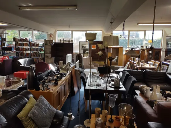 Ruim winkelbinnenruimte met meubels, boekenkasten, zithoeken en diverse tweedehands spullen uitgestald