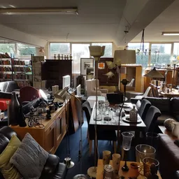 Ruim winkelbinnenruimte met meubels, boekenkasten, zithoeken en diverse tweedehands spullen uitgestald