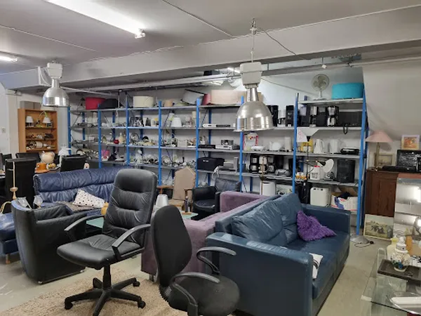 Winkelvloer met zitmeubels, blauwe stellingen met diverse artikelen en industriële hanglamp