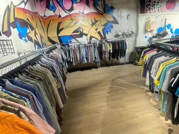 Winkelinterieur met kledingrekken en graffiti-kunstwerk op de muur