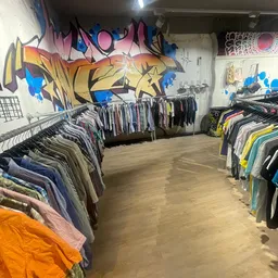 Winkelinterieur met kledingrekken en graffiti-kunstwerk op de muur