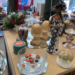 Uitstallingtafel met decoratieve objecten, bloemen, kasten en huishoudspullen