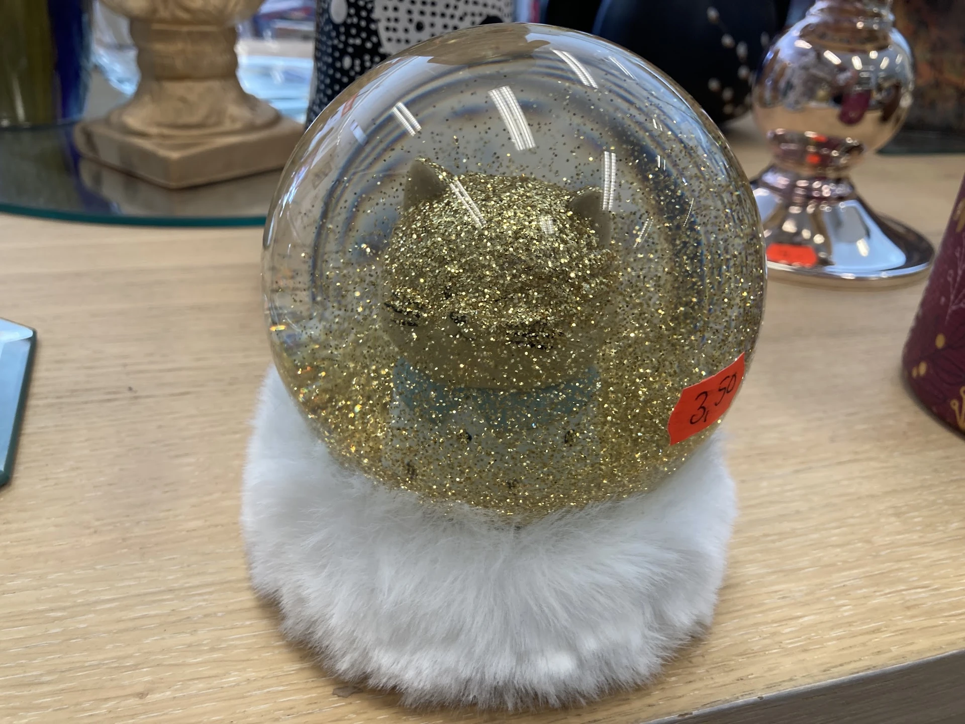 Sneeuwbol met gouden glitter en witte nepbont voet op houten tafel