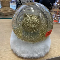Sneeuwbol met gouden glitter en witte nepbont voet op houten tafel