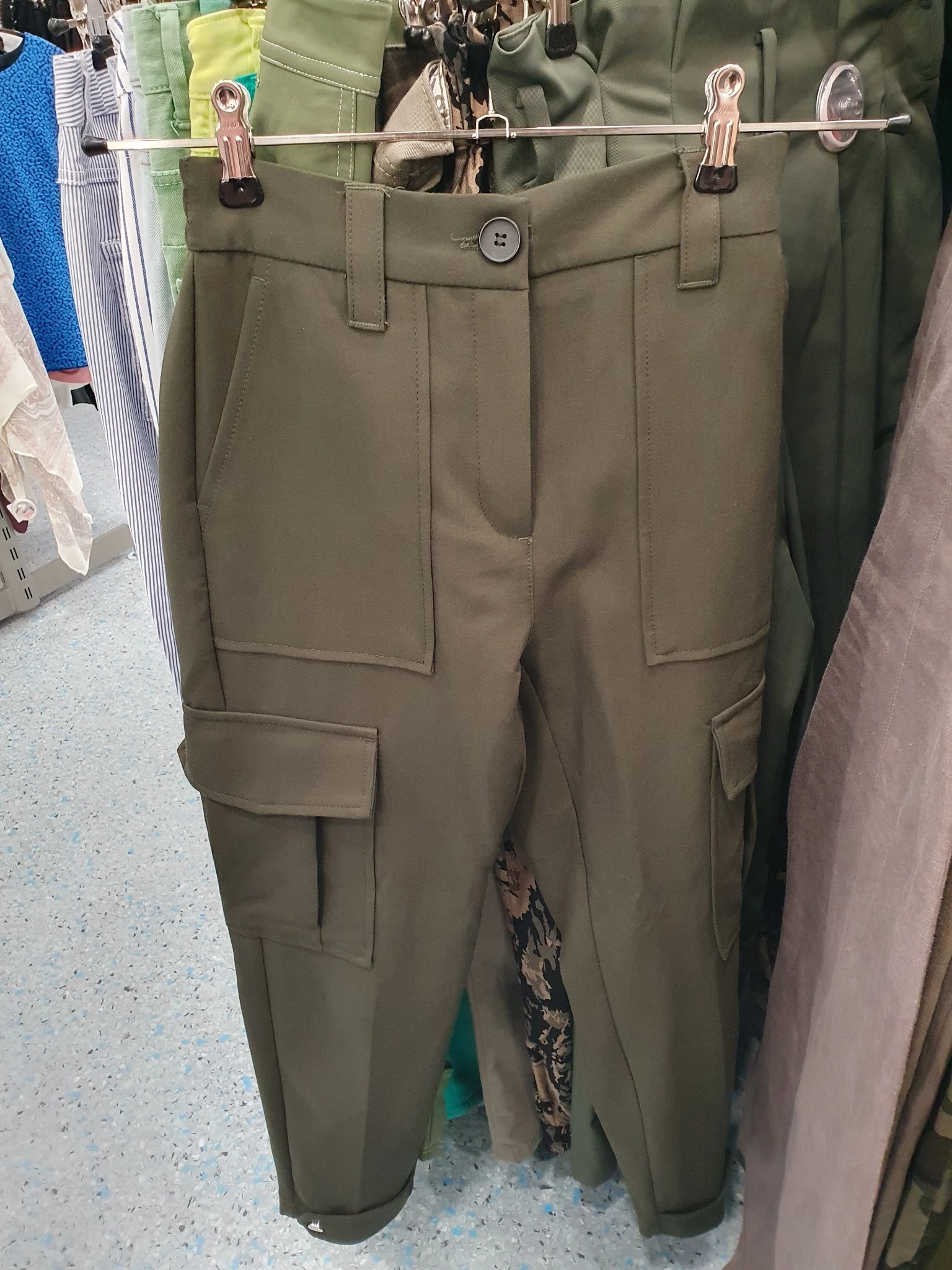 Close-up van een khaki/beige cargobroek met meerdere zakken, uitgestald in de winkel