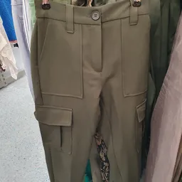 Close-up van een khaki/beige cargobroek met meerdere zakken, uitgestald in de winkel