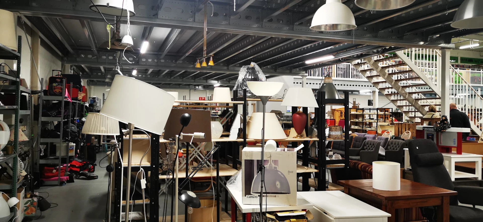 Winkelvloer met uitgestalde meubels, lampen en huisraad in een kringloopwinkel