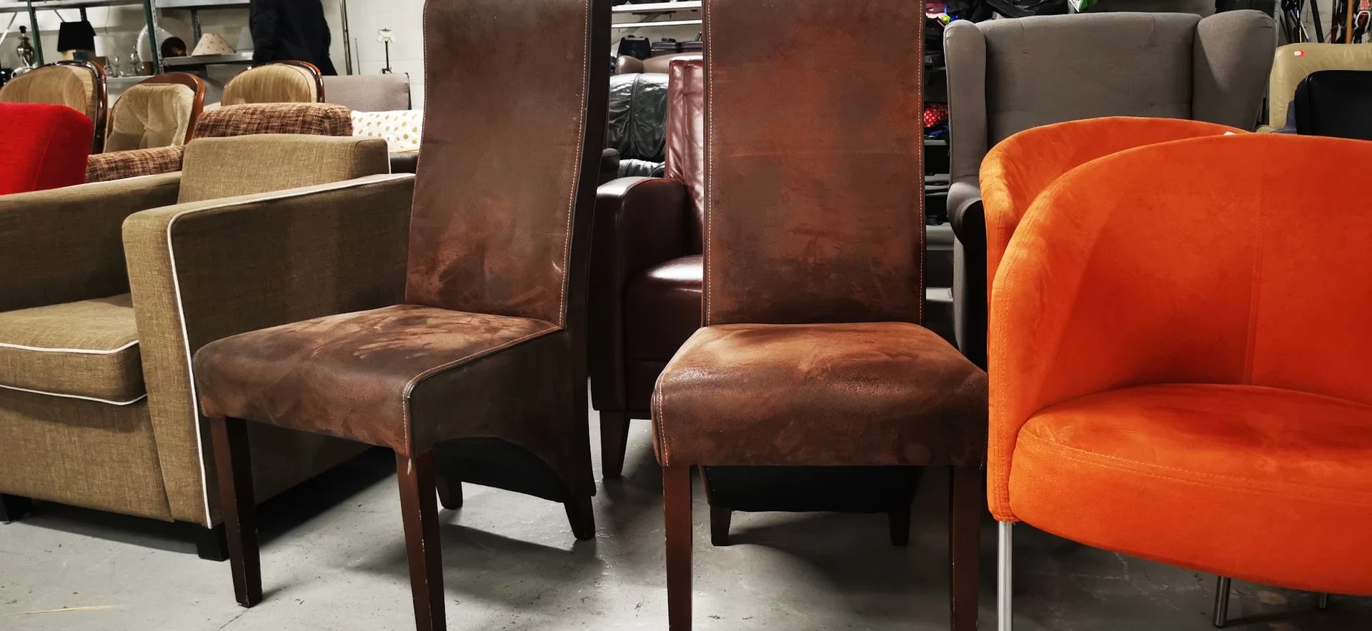 Bruinleren eetkamerstoelen en oranje fluwelen stoel in de winkel