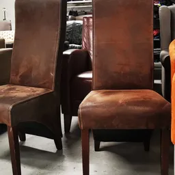Bruinleren eetkamerstoelen en oranje fluwelen stoel in de winkel