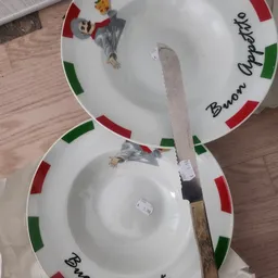 Twee witte borden met Italiaanse vlag en text, met een mes ernaast