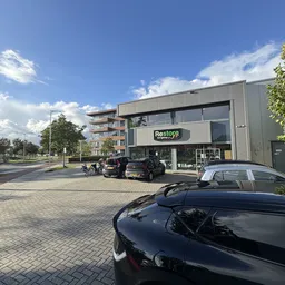 Gevelaanzicht van Restore kringloopwinkel met parkeerplaats en fietsers