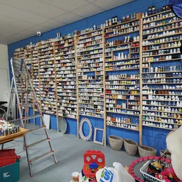 Wanden vol blauwe stellingen met huishoudelijke artikelen en serviesgoed in een kringloopwinkel