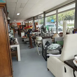 Winkelvloer van kringloopwinkel met diverse gebruikte huishoudelijke artikelen, meubels en decoratieve items op stellingen