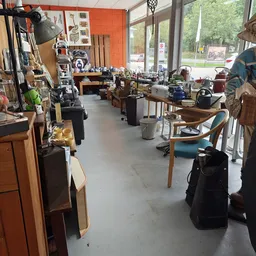 Winkelvloer van kringloopwinkel met meubels, stoelen, kasten en diverse gebruiksartikelen langs de zijkanten