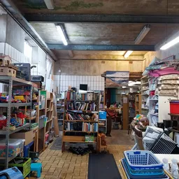 Winkelinterieur met boekenrekken, speelgoed, kleding en diverse tweedehands spullen op stellingen