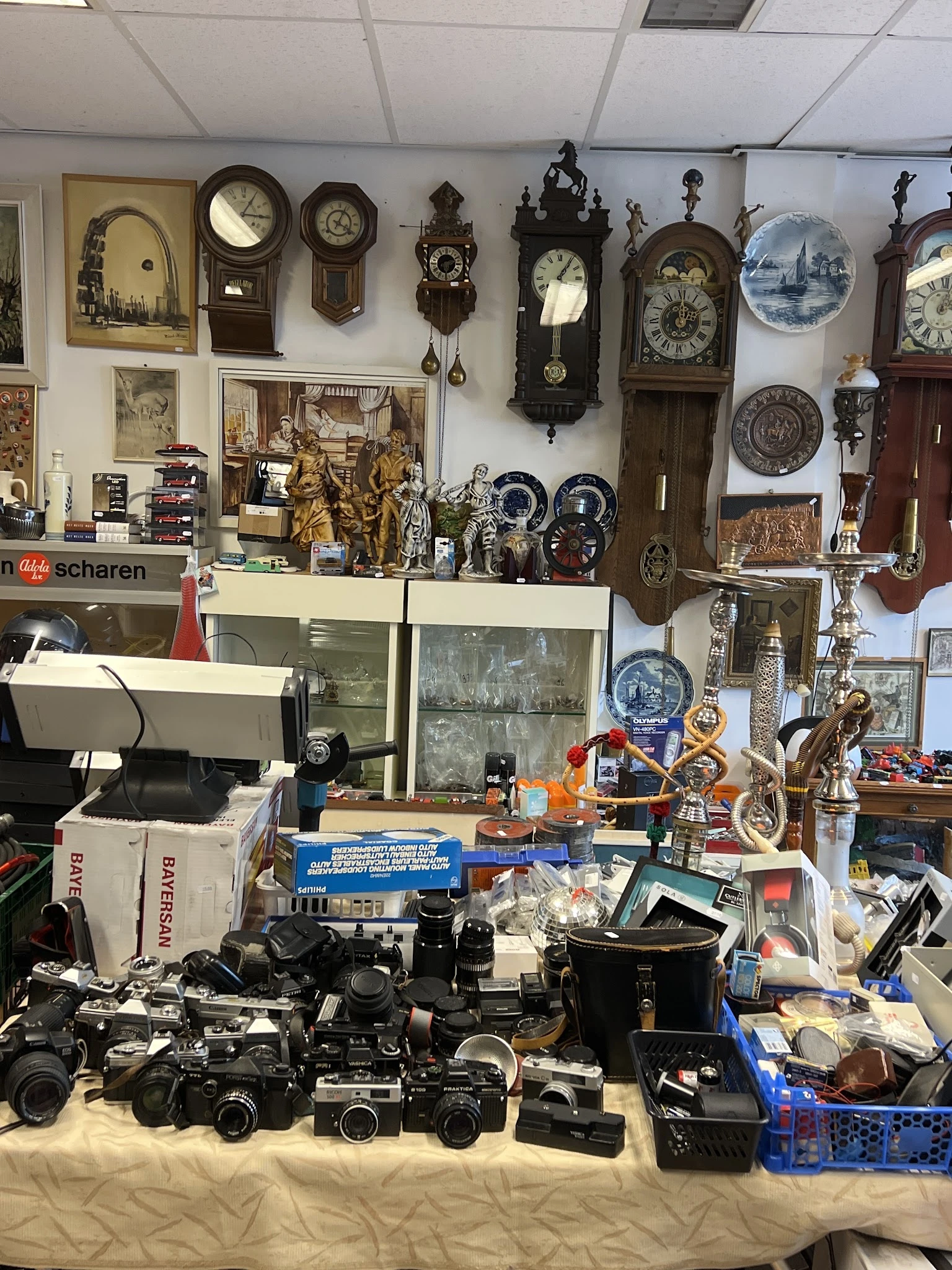 Vitrinekast en werkbank met verzameling antieke klokken, beeldjes, servies en decoratieve voorwerpen
