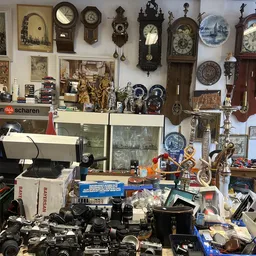 Vitrinekast en werkbank met verzameling antieke klokken, beeldjes, servies en decoratieve voorwerpen