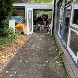 Doorgang naar winkelruimte met uitgangen, rommel en opgestapelde spullen aan de zijkanten