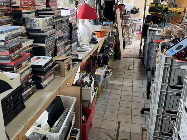 Winkelvloer van kringloopwinkel met rekken, dozen en stapels artikelen langs de wanden