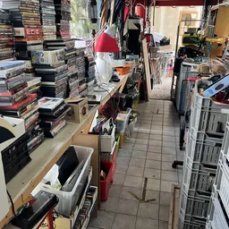 Winkelvloer van kringloopwinkel met rekken, dozen en stapels artikelen langs de wanden