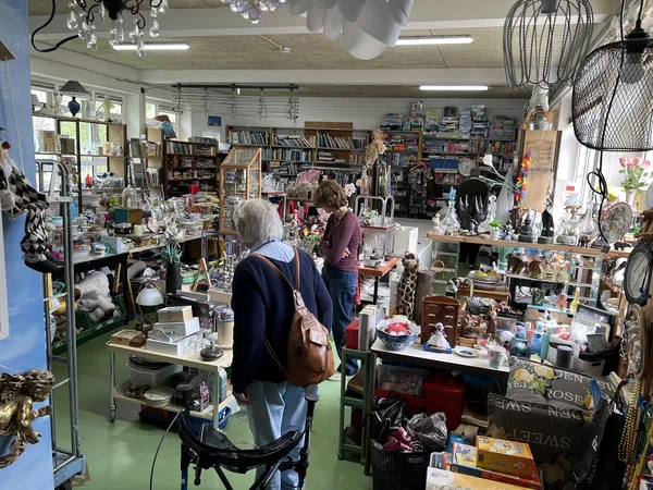 Winkelvloer van een kringloopwinkel vol met diverse tweedehandsartikelen, boeken, huishoudspullen en decoratie op stellingen 