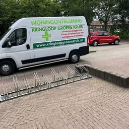 Bedrijfsbus van Kringloop Groene Kruis met winningontruiming informatie geparkeerd op straat