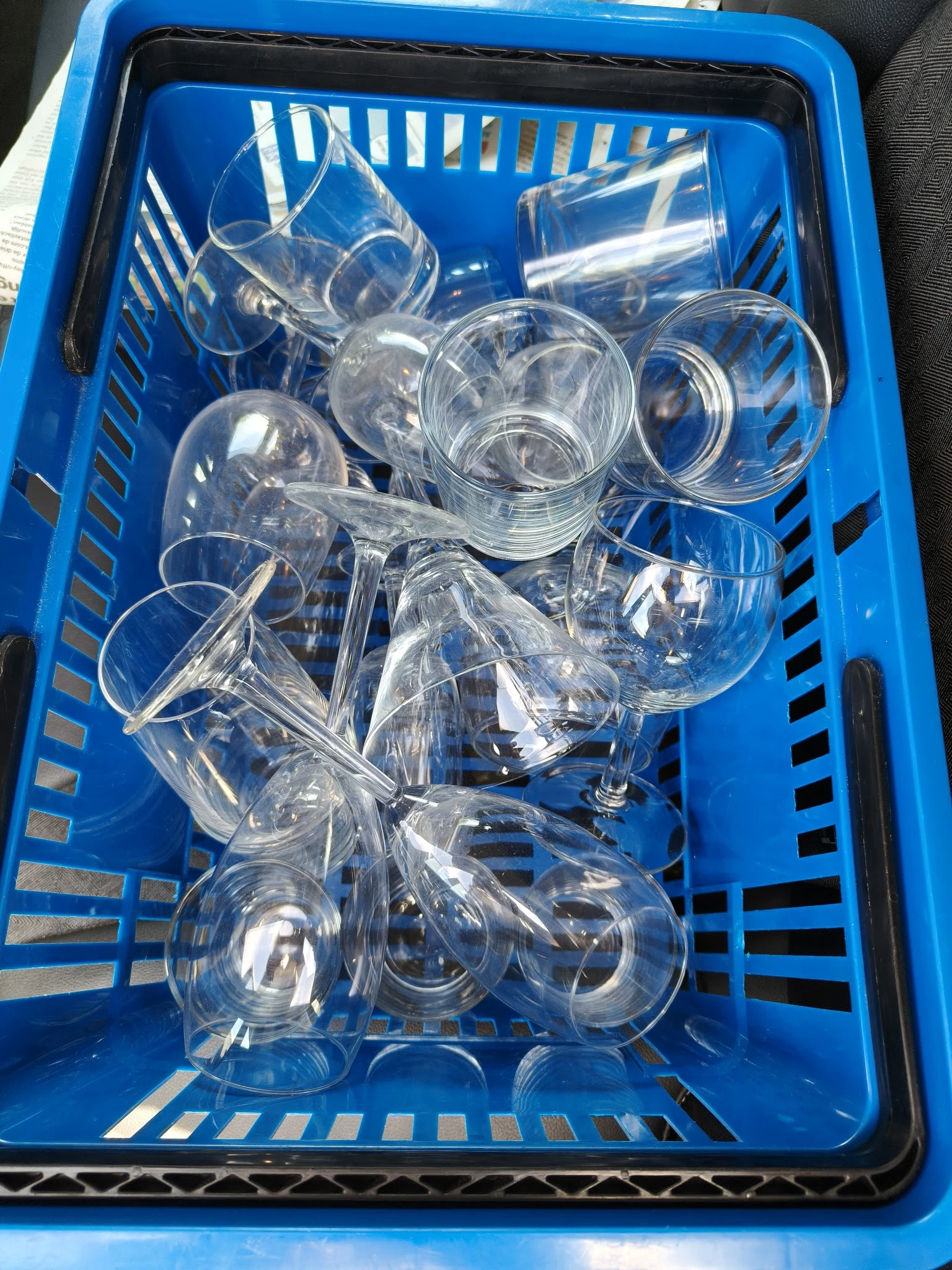 Blauwe krat vol met transparante glazen bekers en drinkglazen
