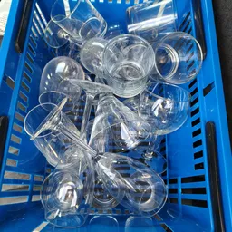 Blauwe krat vol met transparante glazen bekers en drinkglazen