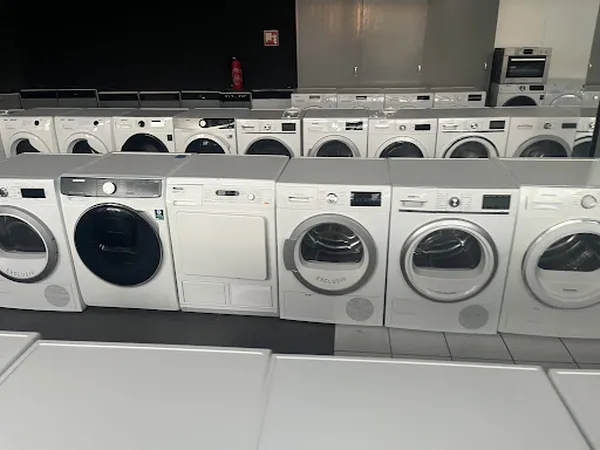 Rij met tweedehands wasmachines en droogkasten uitgestald in de winkel