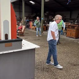 Binnenzicht van kringloopwinkel met bezoekers en diverse tweedehands meubelstukken