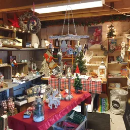 Winkelvloer met kerstversiering, rode tafels vol spullen en stellingen tegen de muren met kerstdecoraties en huishoudelijke a
