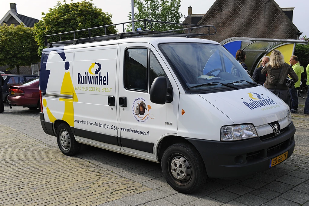 Bedrijfsbus van Ruilwinkel met geel-wit logo en huisstijl, geparkeerd op straat