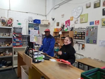 Twee vrijwilligers werkzaam achter de toonbank in de kringloopwinkel