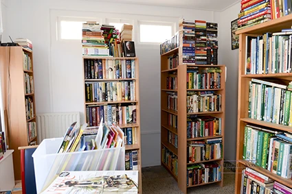 Boekenkasten met dvd's en boeken langs de wanden in een kringloopwinkel