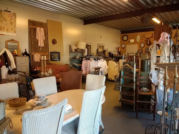 Winkelvloer van kringloopwinkel met tafels, stoelen, kledingrekken en huishoudelijke spullen
