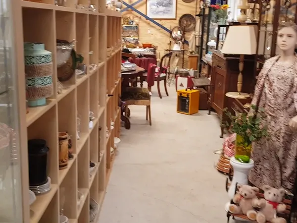 Winkelinterieur met houten stellingen vol spullen, meubilair en decoratie langs het gangpad