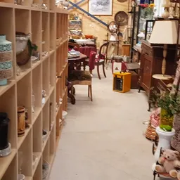Winkelinterieur met houten stellingen vol spullen, meubilair en decoratie langs het gangpad