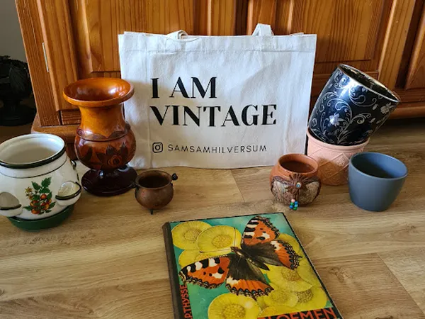 Vintage items op houten tafel: keramische potten, kandelaar, borden en decoratief boek met vlinders