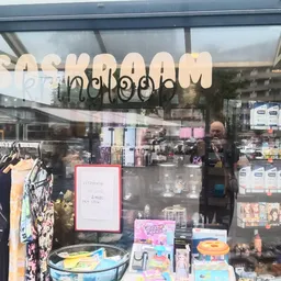 Winkelruit met naam 'saskraam' boven de deur, uitstalraam met kleding en diverse spullen zichtbaar