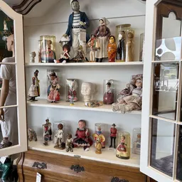 Glazen vitrinekast met verzameling poppen en beeldjes in verschillende stijlen en maten
