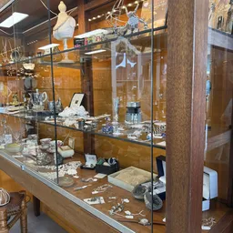 Glazen vitrinekast met zilverwerk, servies, sieraden en andere luxe artikelen uit de kringloopwinkel
