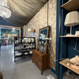 Interieur van kringloopwinkel met houten meubels, stellingen, spiegels en lampen