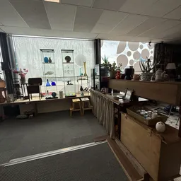 Winkelinterieur met uitgestalde spullen op planken, toonbank en decoratieve items bij ramen