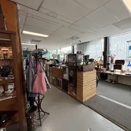 Winkelvloer met houten toonbanken, stellingen met kleding, huisraad en diverse tweedehandsartikelen
